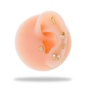 Macro shot of gold G23 titanium cartilage studs with zirconia butterfly and clover designs