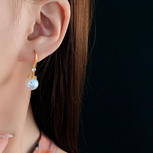 Close-up of 14K gold plated hook earrings featuring white pearl and blue zircon