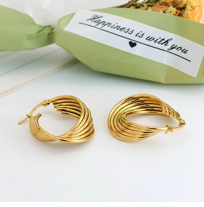 Macro view of multi-layer twisted gold hoop earrings with polished metal finish and clasp