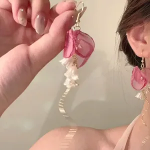 Detail of pink fabric flower earrings with white lily pendants and golden long tassels