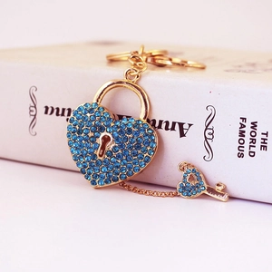 Blue rhinestone heart lock keychain with golden key on elegant white background