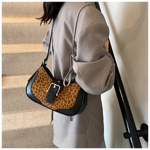 Détail du sac léopard avec bandoulière en cuir noir et boucle métallique sur le côté