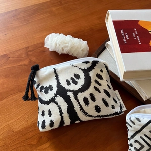 Close-up of bohemian linen coin purse with black and white abstract print on wood desk