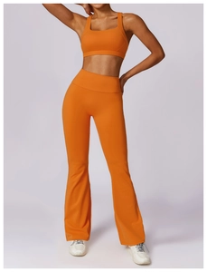 Detail of high-waist flared yoga pants and racerback sports bra in bright orange finish