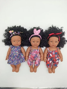 Detailed view of three black baby dolls in colorful floral outfits on a white background