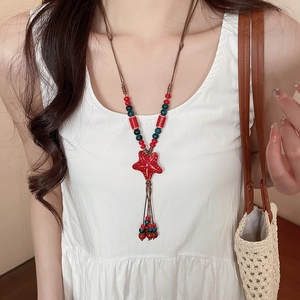 Detail of a handmade ceramic necklace featuring a red starfish pendant and colorful beads