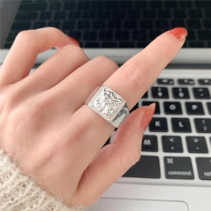 Macro detail of silver square ring with molten lava texture on woman finger