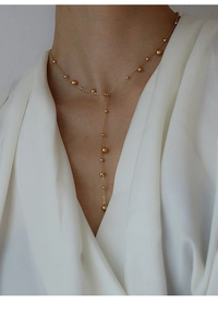 Detail of 18k gold plated Y-shaped beaded necklace on white silk shirt worn by a model