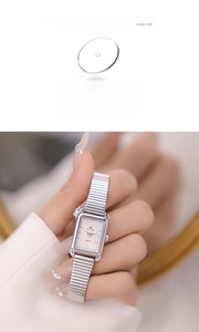 Macro detail of silver rectangular watch with elastic metal band and Roman numerals