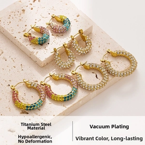 Detailed macro of gold titanium steel hoop earrings featuring colorful paved rhinestones