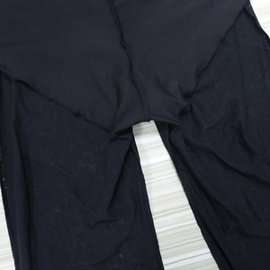 Detailed view of black high-waist flared pants showing stitching and sheer mesh fabric
