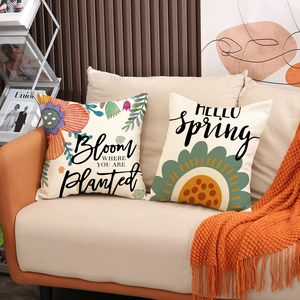 Linen decorative floral pillow covers with Bloom and Hello Spring text on a beige sofa