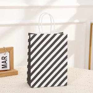 Halloween gift bag with black and white diagonal stripes and white rope handles on lace table