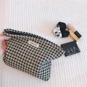 Close-up of black and white houndstooth cosmetic bag with woven fabric and metal zipper