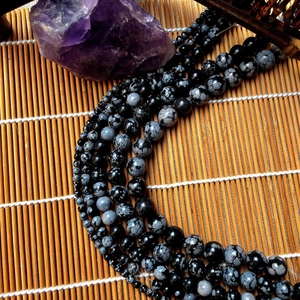 Macro shot of natural snowflake obsidian round beads with grey spot texture for jewelry