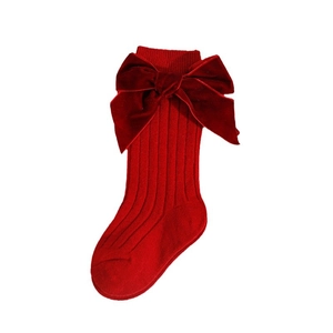 Red knit baby socks with oversized velvet bow detail on a clean white background