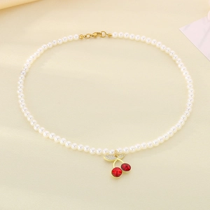 Detailed close-up of pearl necklace featuring a red resin cherry pendant with diamond leaf