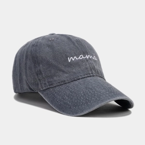 Detail of white mama embroidery on washed dark grey cotton baseball cap