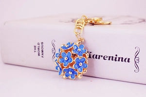 Macro detail of golden keychain with blue enamel flower sphere pendant and gold ring