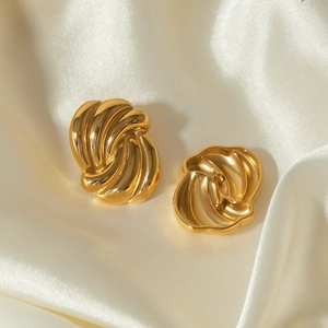 Detailed view of 18k gold plated wave earrings on beige silk background