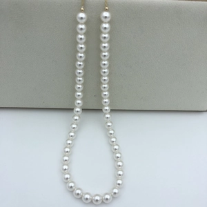 Close-up of white round pearls with high luster on a gold-plated adjustable chain