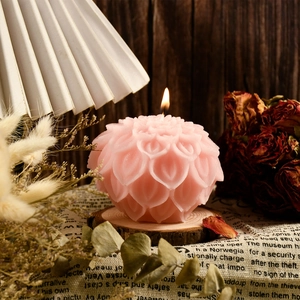 Pink lotus flower candle lit on a wooden base with a warm vintage home decor setup