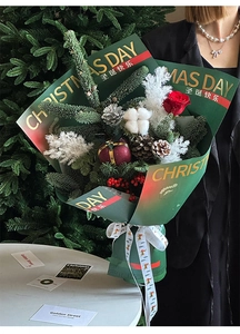Close-up of luxury dark green gold-stamped Christmas bouquet paper with festive ribbons