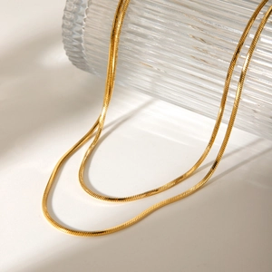 Minimalist double-layered 18K gold-plated snake chain necklace on glass bottle