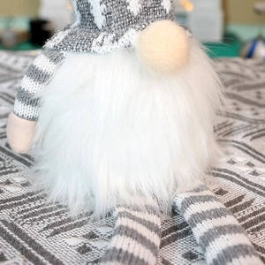 Detailed view of handmade Christmas gnome showing soft white plush beard and grey knit hat