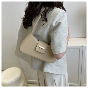 Detail showing high-quality beige leather bag with a gold buckle worn with an office outfit