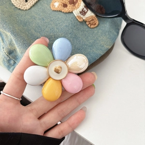 Detail of colorful flower-shaped phone grip with a golden heart center on a resin surface