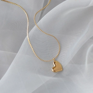 Detailed close-up of a polished gold heart pendant with a delicate twisted rope chain
