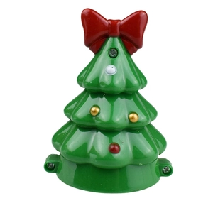 Close-up of a green plastic clockwork Christmas tree toy with a red bow and dot patterns