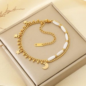 Detail of gold-plated double-layer bracelet with star and moon charms on jewelry box