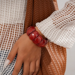 Close-up of red glitter acrylic segment bracelet on model with a bohemian crochet top