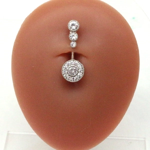 Detailed view of silver belly ring with zircon wing design on a human model