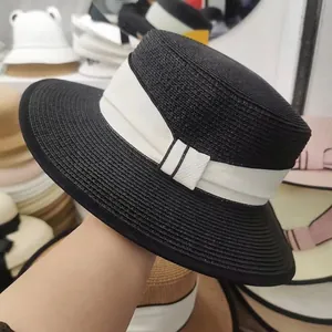 Detail of a black straw boater hat featuring a wide white ribbon and elegant bow accent