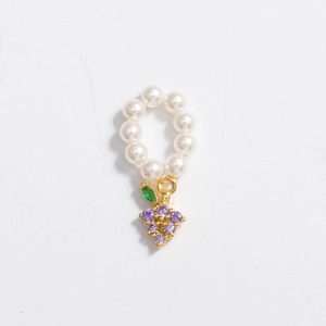 Macro detail of pearl charm necklace with a gold grape pendant featuring purple crystals