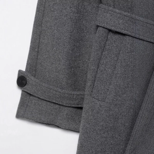 Detailed texture of grey wool coat showing high-quality fabric and sleeve strap design