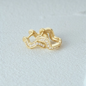 Macro shot of 925 silver wavy gold earrings with micro-set white cubic zirconia