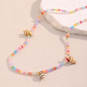 Close-up of colorful beads and conch shell charms on an 18K gold stainless steel necklace