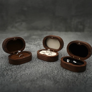 Three oval walnut wood jewelry boxes with diverse inner linings showing rings and studs