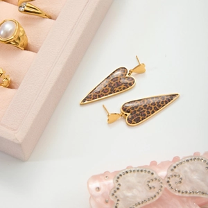 Detailed close-up of heart-shaped earrings with leopard print and gold metal finish