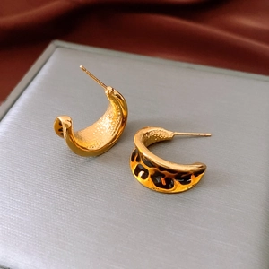 Macro detail of gold C-shaped earrings with vintage leopard print enamel finish