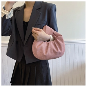 Pink fabric dumpling bag featuring a knotted handle and textured finish for casual style