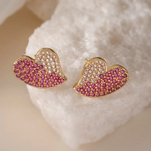 Vue macro de boucles d'oreilles cœur dorées avec oxydes de zirconium roses et blancs