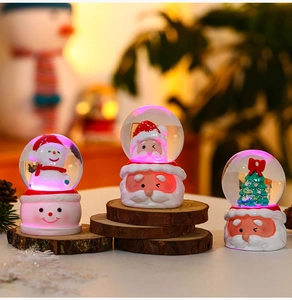 Glow-in-the-dark Christmas snow globes with Santa and snowman figures on wood bases