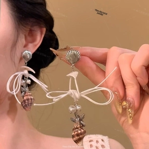 Detail of beach style drop earrings with silver starfish, white shell and pearl pendants
