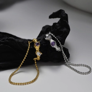 Macro detail of textured gold and silver rings with purple gems on black fabric