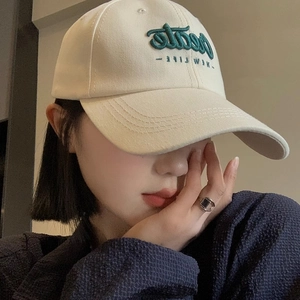 Close-up of beige cotton baseball cap with green embroidered Create NEW LIFE text